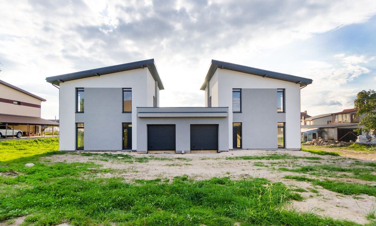 services-02 Front view of twin modern houses with a symmetrical architectural design under a cloudy sky.
