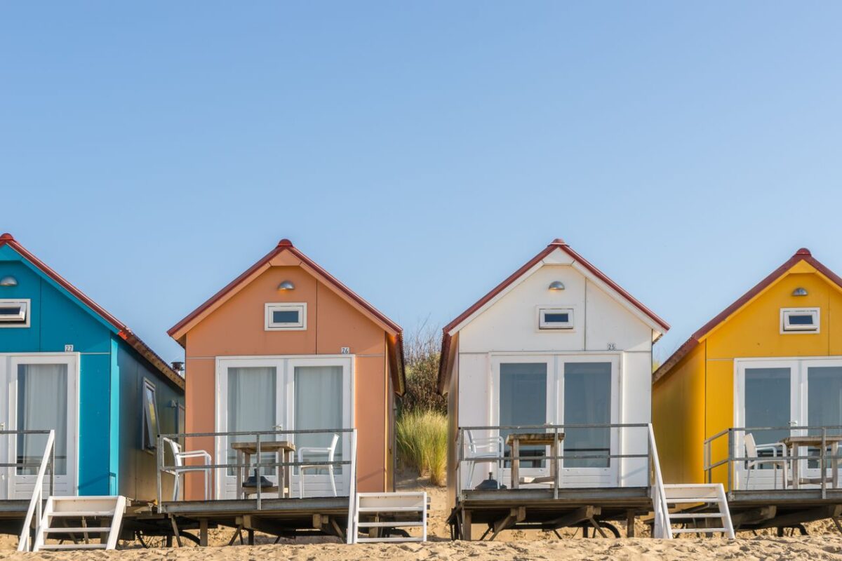 Promotion Rue 66 Vibrant bungalows on a sandy beach with clear blue sky, perfect for vacation vibes.